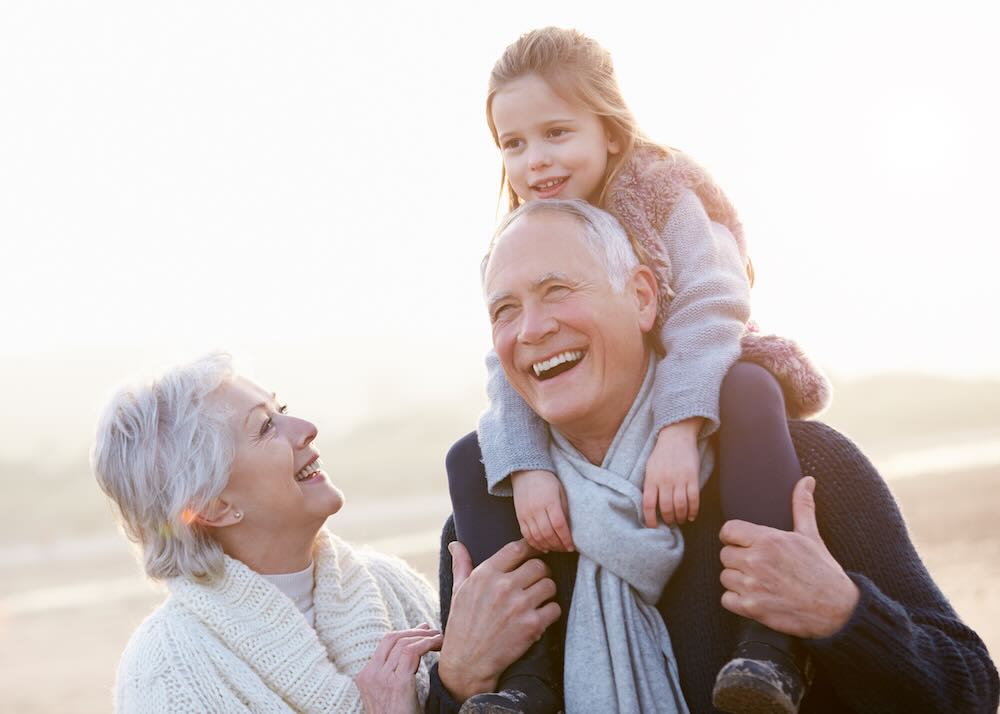 Grandparents with a granddaughter smiling at a camera